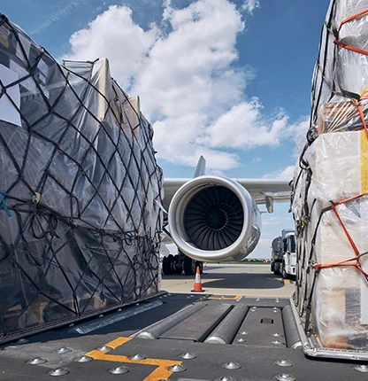 Netted air freight pallets on the apron beside a freighter aircraft engine